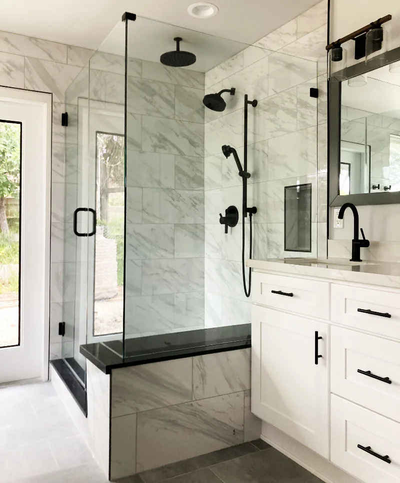 Marble shower with matte black fixtures and white vanity