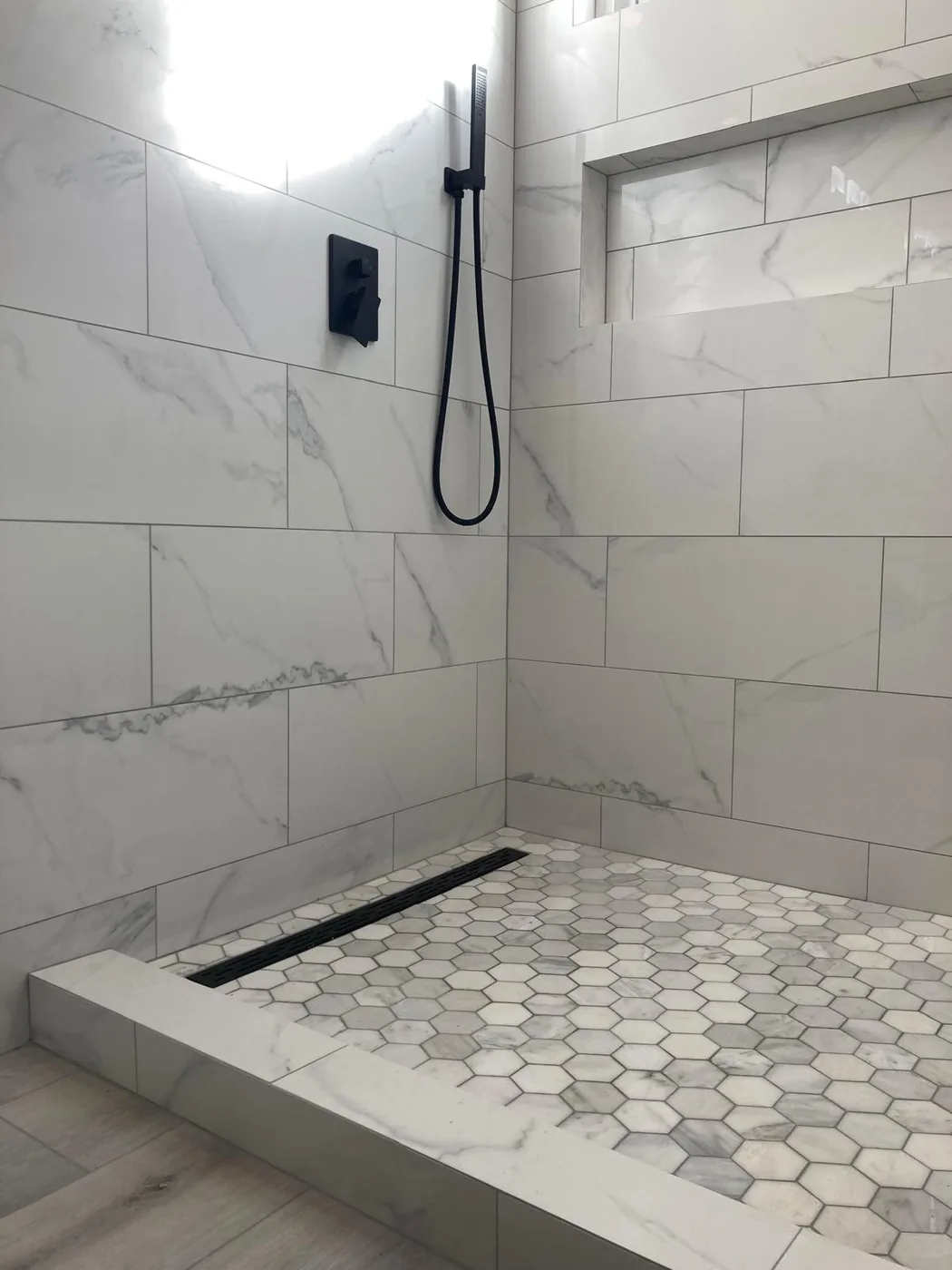 Marble walk-in shower with hex-tile floor